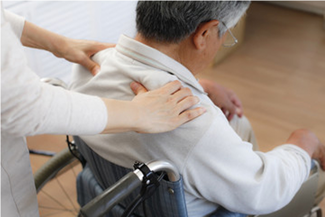 車椅子に乗っている男性を肩揉みする様子
